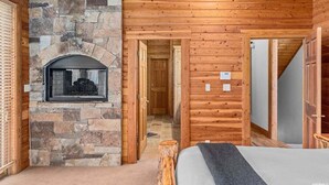 A log cabin room with a stone fireplace, wooden walls, and a bed. - SUN RIDGE - 6 BD, VIEWS, POOL TABLE, HOT TUB (Sundance)