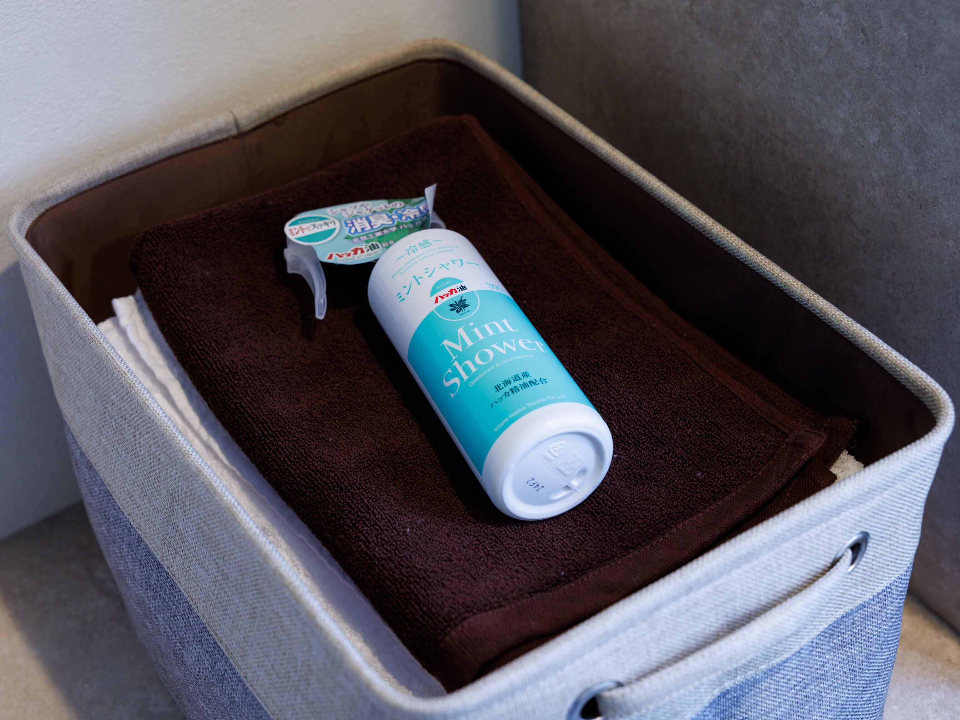 A suitcase with a brown towel and a bottle of 'Min Shower' body wash.