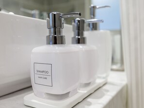 Two white shampoo bottles with pumps on a white shelf in a bathroom.