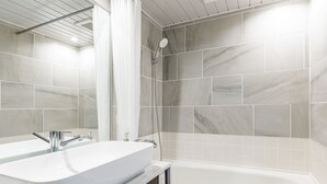 Une salle de bain moderne dotée d’une grande baignoire, d’un meuble-lavabo à deux vasques et d’un espace douche.