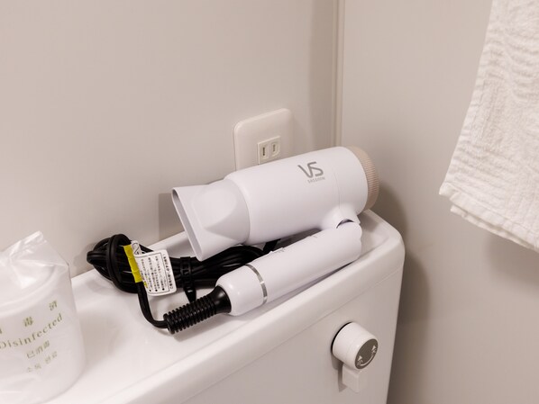 A bathroom with a white toilet, a hairdryer, a bottle of disinfectant, and a towel hanging on the wall. - Tabist MENTEL Kitami (Kitami)
