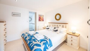A bedroom with a bed, a bedside table, a mirror, and a door. - Beachcomber, Aldeburgh (Suffolk)