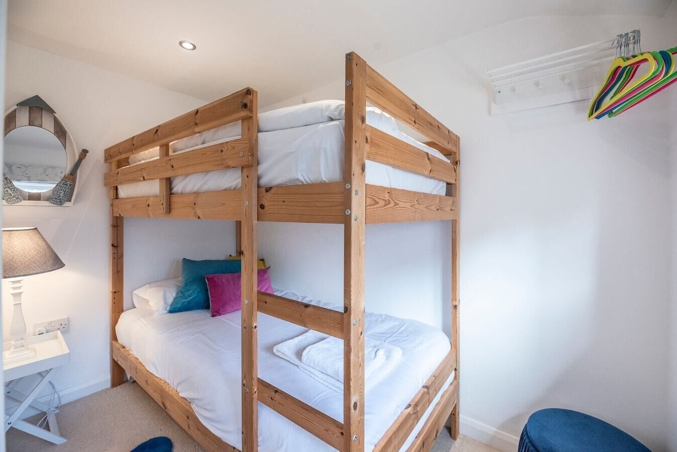 Une chambre avec un lit superposé, un bureau et une chaise, un miroir et une fenêtre.