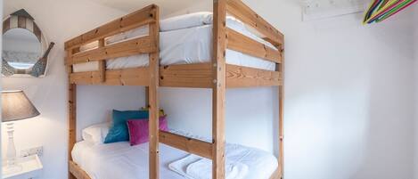 Une chambre avec un lit superposé, un bureau et une chaise, un miroir et une fenêtre.