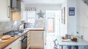 A modern kitchen with a gas stove, white cabinets, and a star decoration on the wall. - Beachcomber, Aldeburgh (Suffolk)