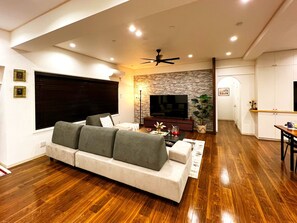 Uma sala de estar moderna com um sofá, uma TV de tela plana e uma parede decorada com pedra.