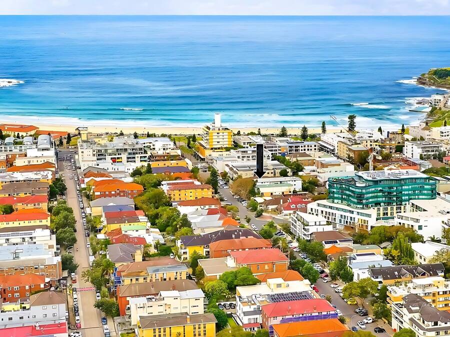Une ville côtière aux bâtiments aux couleurs vives, avec une plage et un phare.