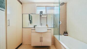 A modern bathroom with a glass shower enclosure, a sink, and a toilet.