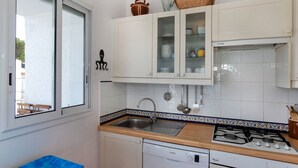 A compact kitchen with white cabinets, a Bosch dishwasher, a Whirlpool stove, and a window with a view of the outside. - Graciosa Blanco by Interhome (Llançà)