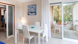 A modern dining area with a white table and chairs, a painting of sailboats on the wall, and a balcony with a glass door. - Mediterrani by Interhome (Llançà)