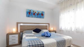 A neatly arranged bedroom with a wooden headboard, a quilted bedspread, and a painting above the bed. - Mediterrani by Interhome (Llançà)