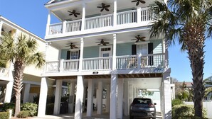 A multi-story building with a balcony, a car parked in front, and palm trees. - The Blue Pearl - Walk to the Beach in Garden City (Garden City Beach)