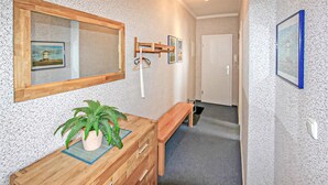 A hallway with a wooden bench, a potted plant, and a mirror on the wall.