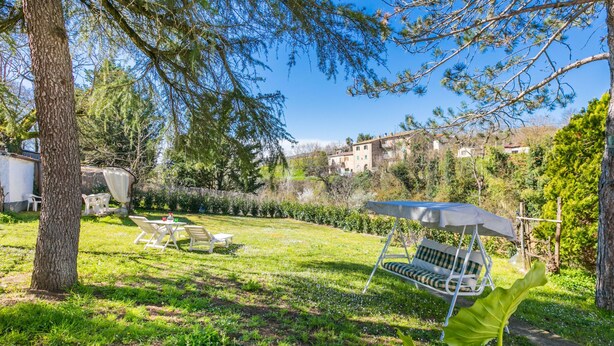 A backyard with a dining area, a swing, and a large tree. - La Casa del Ponte Romano by Interhome (Bucine)