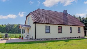 Een herenhuis met twee verdiepingen, een pannendak, een overdekte veranda en een verzorgd gazon.