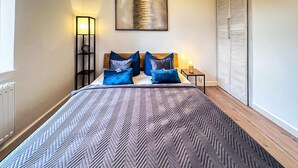 A neatly made bed with a patterned bedspread, a bedside table with a lamp, and a wall-mounted artwork. - Ferienwohnung Blankenhagen (Blankenhagen)