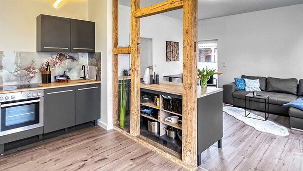 A modern kitchen with a built-in oven and a wooden dining area. - Ferienwohnung Blankenhagen (Blankenhagen)