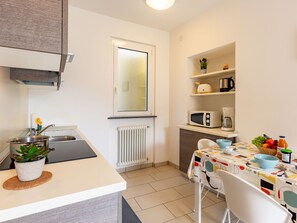 Enjoy meals in this kitchen with a central island, sink, and microwave, adjacent to a dining area for two.