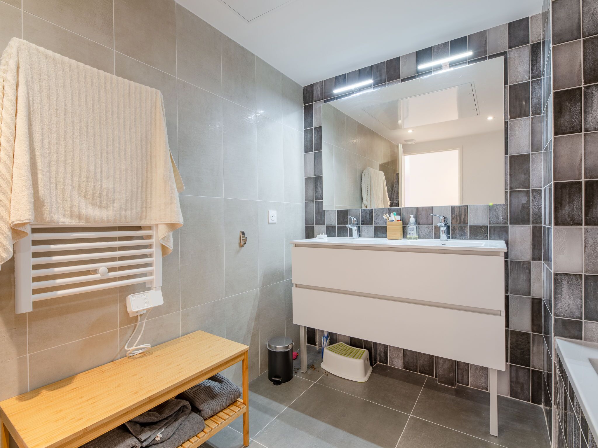 Une salle de bain moderne avec un meuble-lavabo blanc, un miroir et un porte-serviettes.