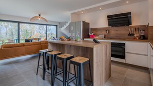 Eine moderne Küche mit einer Holztheke, Barhocker und einem eingebauten Backofen.