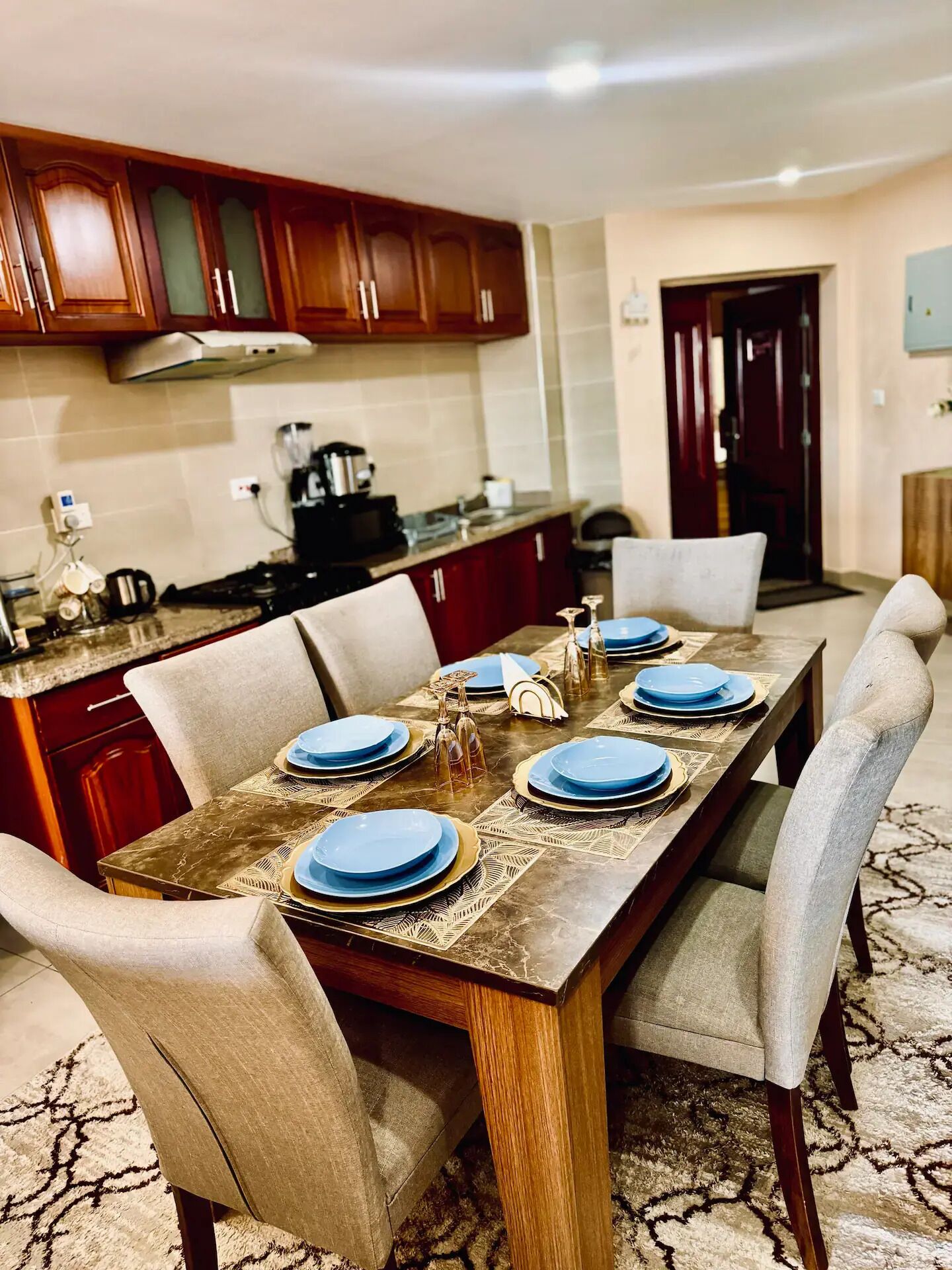 Un comedor con una mesa de madera dispuesta para seis personas, rodeada de sillas color beige.