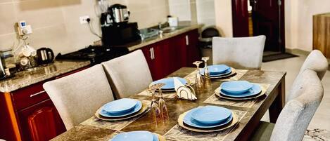 Un comedor con una mesa de madera dispuesta para seis personas, rodeada de sillas color beige.