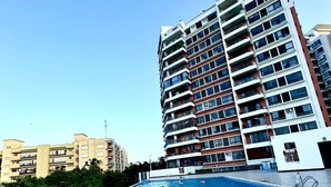 A swimming pool with a tiled edge, surrounded by a high-rise building with multiple balconies.