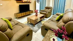 A modern living room with a sofa set, a coffee table, a TV, and a decorative vase.