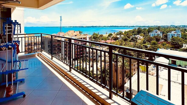 A balcony with a view of the sea and buildings.
