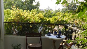 Un balcón con mesa, sillas, plantas en macetas y vistas al verdor.