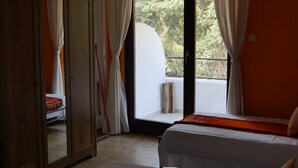 Un dormitorio con cama, armario y balcón con cortinas.