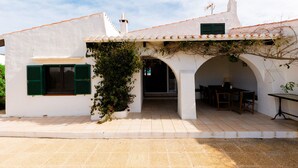 A white building with green shutters, a tiled roof, and an arched entrance. - BINISAGOC B - Charming chalet near the sea with free WiFi (Sant Lluís)