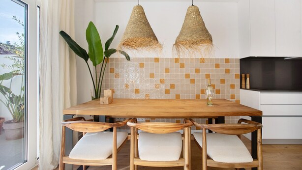 A dining area with a wooden table, four chairs, two hanging wicker lamps, a potted plant, and a tiled backsplash. - Apartment 'Casa Aga Seaside Chic' with Balcony, Wi-Fi and Air Conditioning (Ericeira)