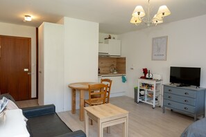 A compact living space with a kitchenette, a dining area, a television, and a small cabinet.