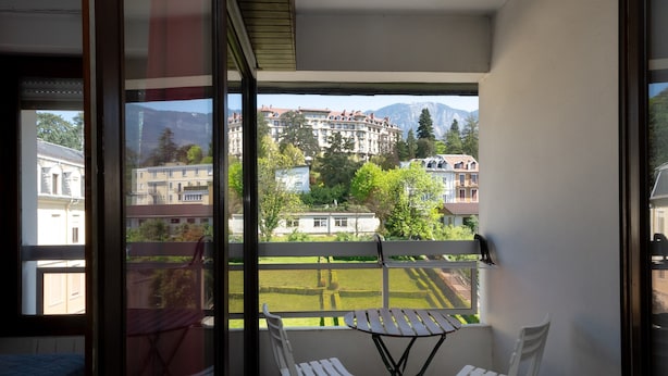 Un balcon avec une table et des chaises, une vue sur des immeubles et une montagne en arrière-plan.
