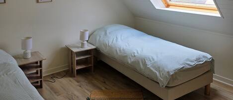 Un dormitorio con tragaluz, cama, mesita de noche, lámpara y una obra de arte en la pared.