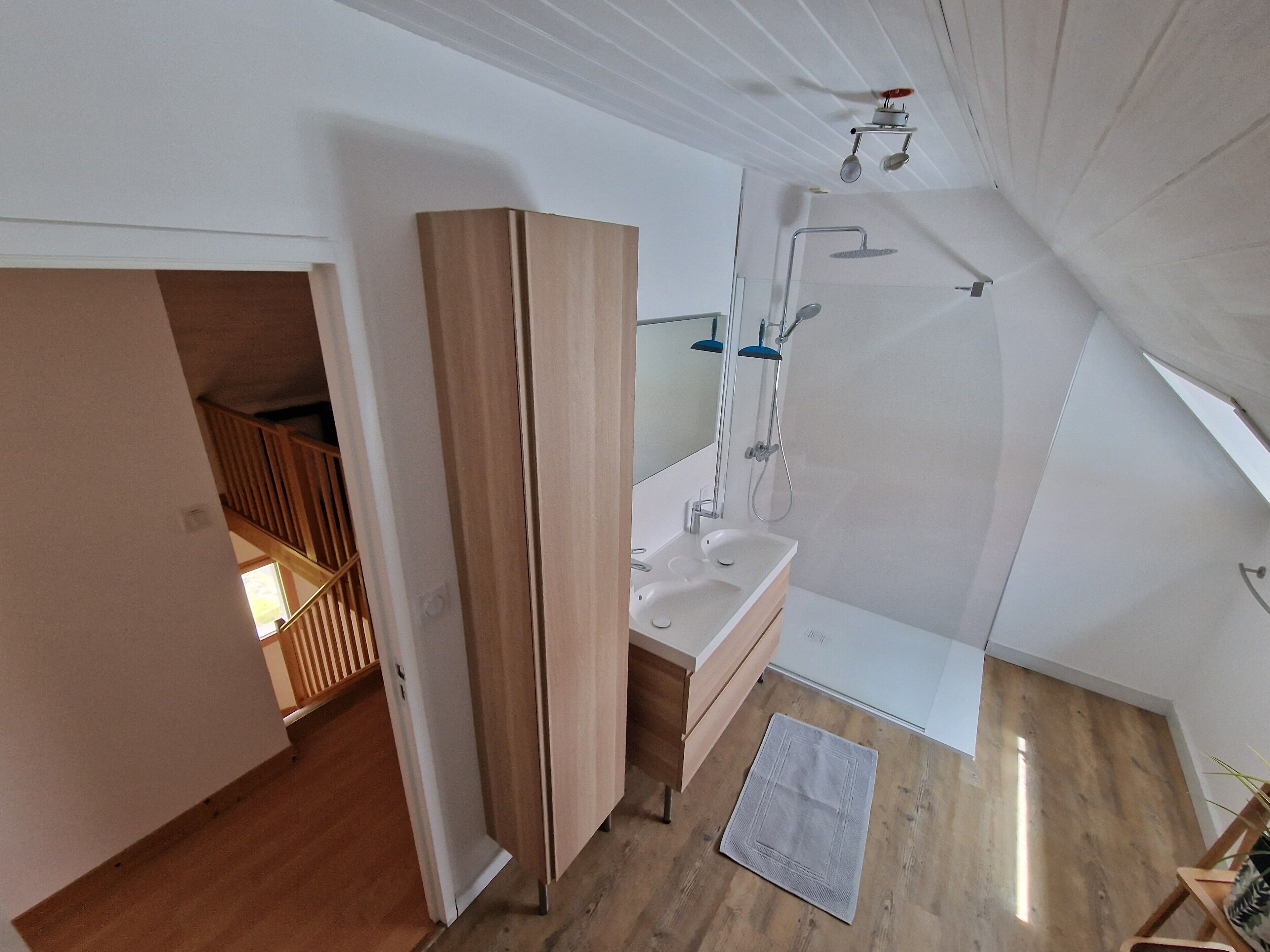 Un baño moderno con ducha, lavamanos y espejo.