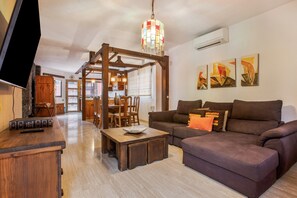 A living room with a wooden coffee table, a sofa, a TV, and a chandelier. - Vacation Home 'Karat Kanaria' with Sea View, Wi-Fi and Air Conditioning (Adeje)