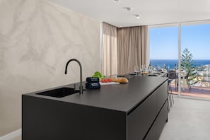 Una cocina moderna con una isla grande, un lavaplatos empotrado y vistas a la ciudad y al mar.