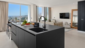 Une cuisine moderne dotée d’un grand îlot central, d’un coin repas avec un canapé et d’un téléviseur fixé au mur.