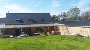 Une maison avec un toit en pente, une véranda et une façade en pierre.