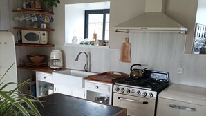 Une cuisine de taille réduite, avec une table en bois, une cuisinière, un four à micro-ondes et un évier.