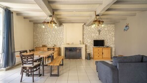A spacious living area with a fireplace, stone wall, wooden furniture, and a television. - Holiday Home 'Maison À Cozes' with Private Terrace, Private Garden and Wi-Fi (cozes)