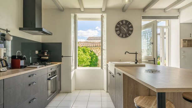 A modern kitchen with a large island, built-in oven, and a view through an open door to the outside. - Holiday Home 'Maison À Cozes' with Private Terrace, Private Garden and Wi-Fi (cozes)