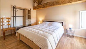 A bedroom with a bed, wooden chair, wardrobe, and a small bedside table with a lamp. - Holiday Home 'Maison À Cozes' with Private Terrace, Private Garden and Wi-Fi (cozes)