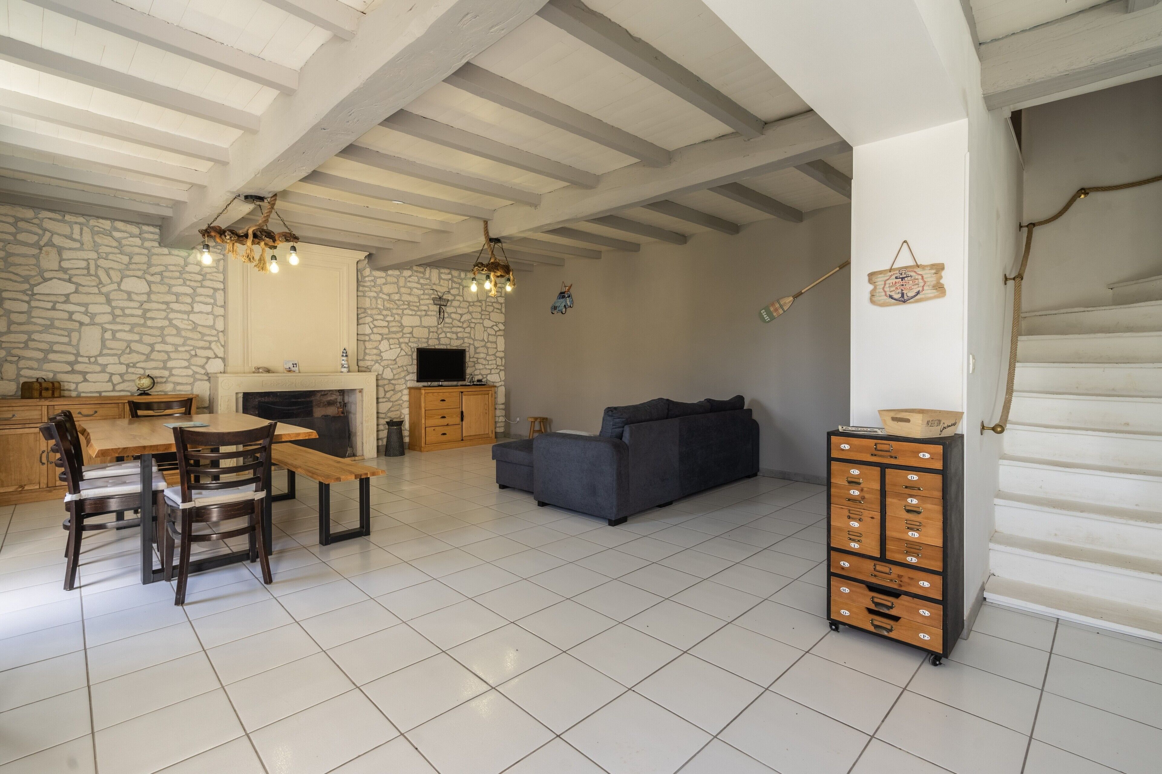 A spacious living area with a stone wall, wooden furniture, a sofa, and a built-in cabinet.