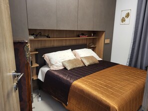 A neatly arranged bedroom with a bed, bedside tables, and a wardrobe.