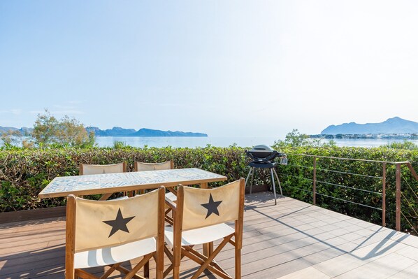 Una terrazza con tavolo e sedie, un barbecue e vista sul mare e sulle montagne.