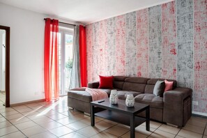 Ein Wohnzimmer mit braunem Sofa, einem Couchtisch und einem roten Vorhang.