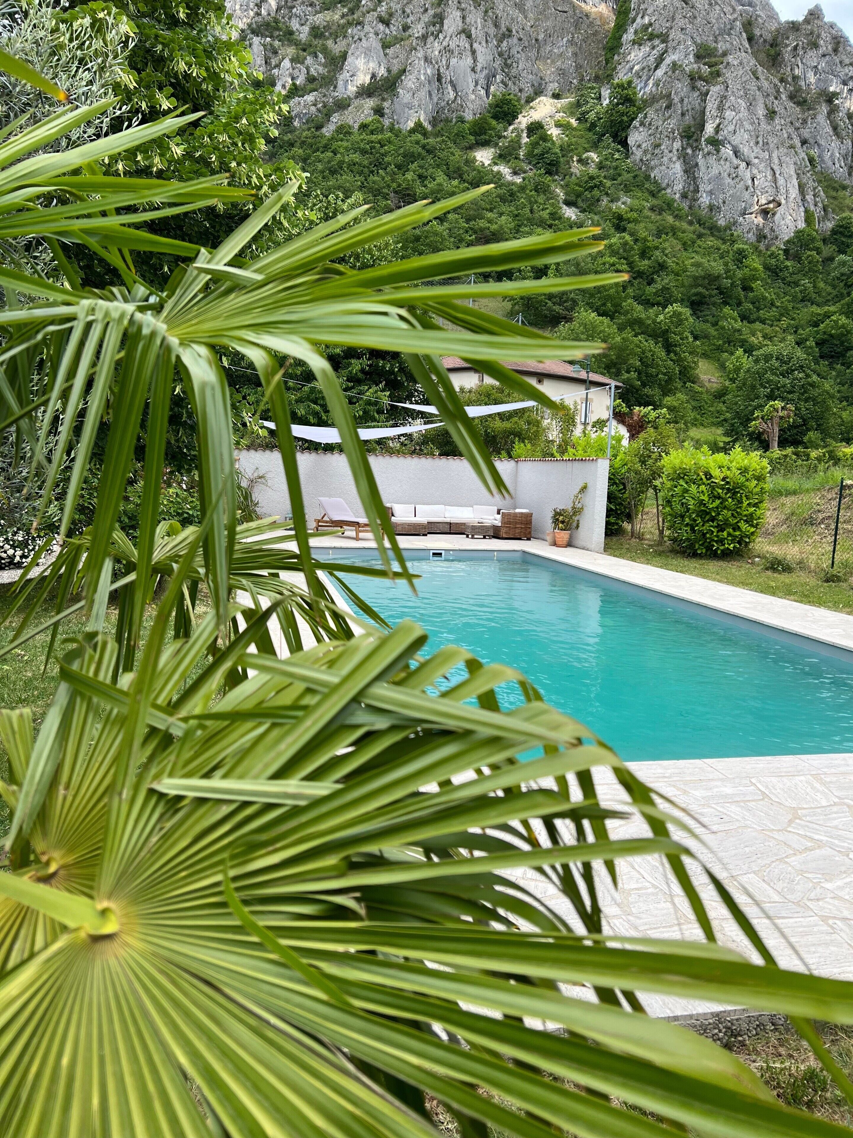 A swimming pool with a view of a mountain and a building with outdoor seating.